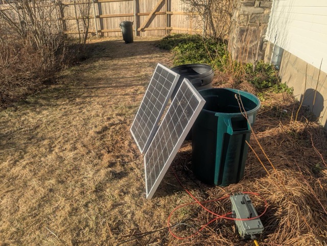 2 100W panels propped up against 2 garbage cans/bins